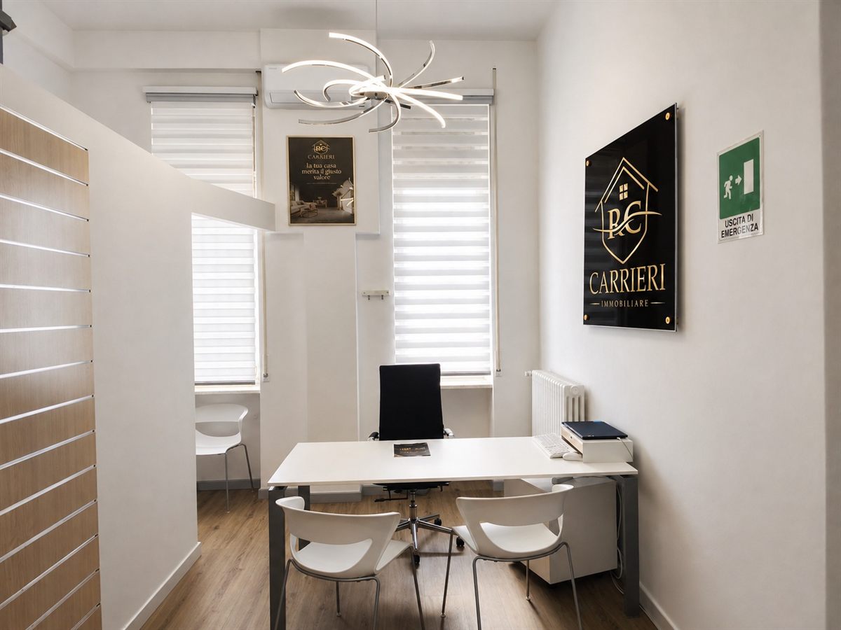 Sala consulenza dell’agenzia con tavolo per gli incontri, lampada di design e ambiente luminoso